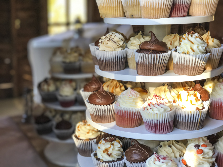 a close up shot of a tiered cupcake tower with different flavors of cupcakes ready for guests to eat